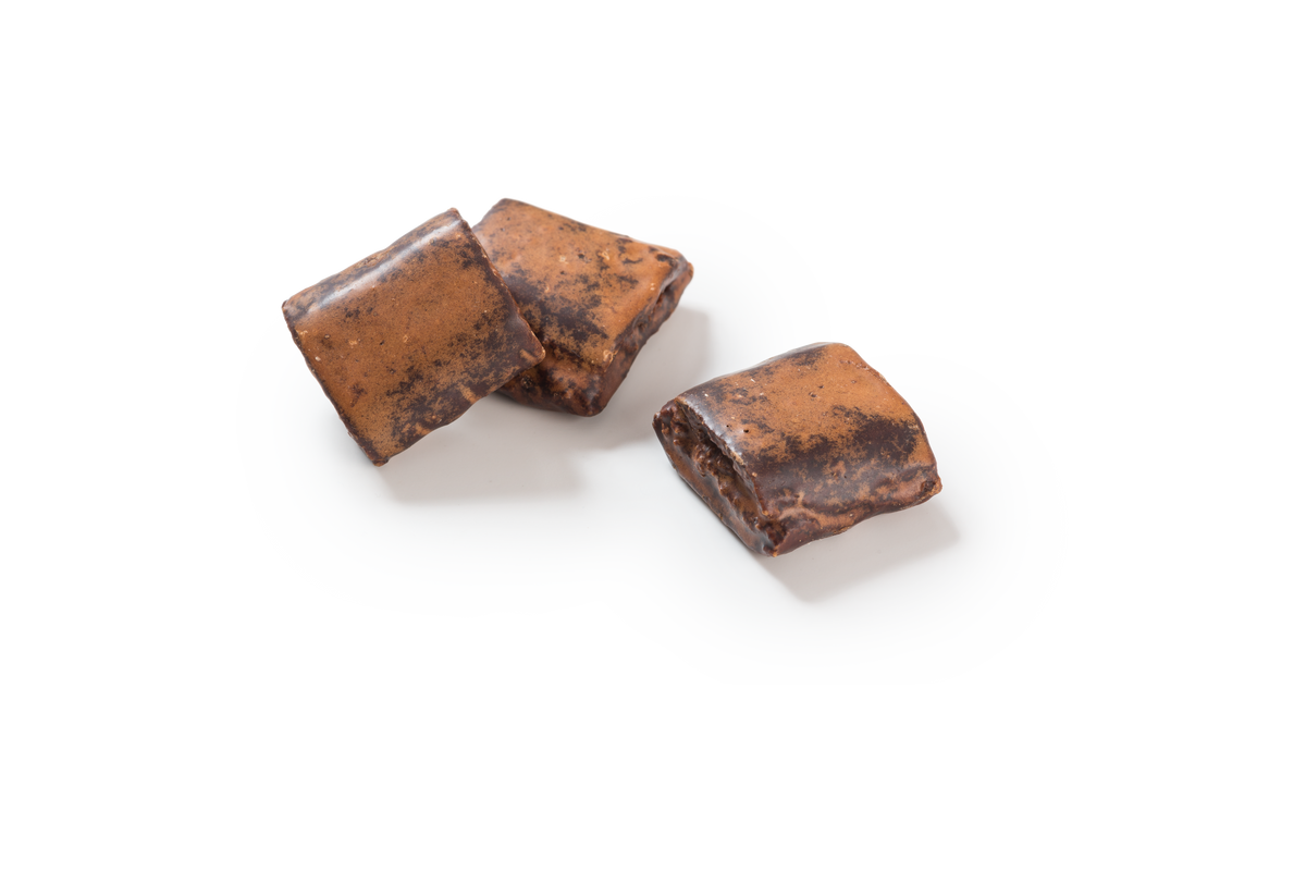 Produktaufnahme von drei Stücken Alpenbrot. Die rechteckigen Lebkuchen sind mit einer Kakaoglasur überzogen, die eine bräunliche, leicht strukturierte Oberfläche aufweist. 