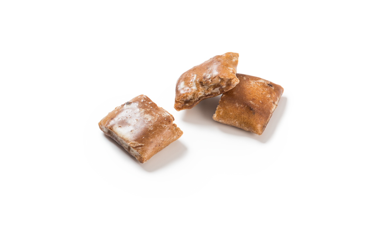 Produktaufnahme von drei Stücken rechteckigen, glasierten Lebkuchen. Die goldbraune Oberfläche ist mit einer feinen, weißen Zuckerglasur überzogen. Die Schnitt- oder Bruchflächen lassen die innere Struktur mit sichtbaren getrockneten Apfelstückchen erahnen.