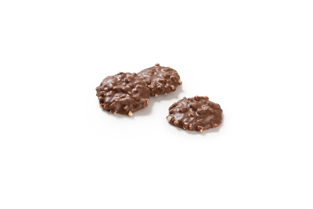 Produktaufnahme von drei Haselnusstalern. Die runden Kekse sind vollständig mit Vollmilchschokolade überzogen und haben durch die eingearbeiteten Haselnüsse eine charakteristisch unebene Oberfläche.