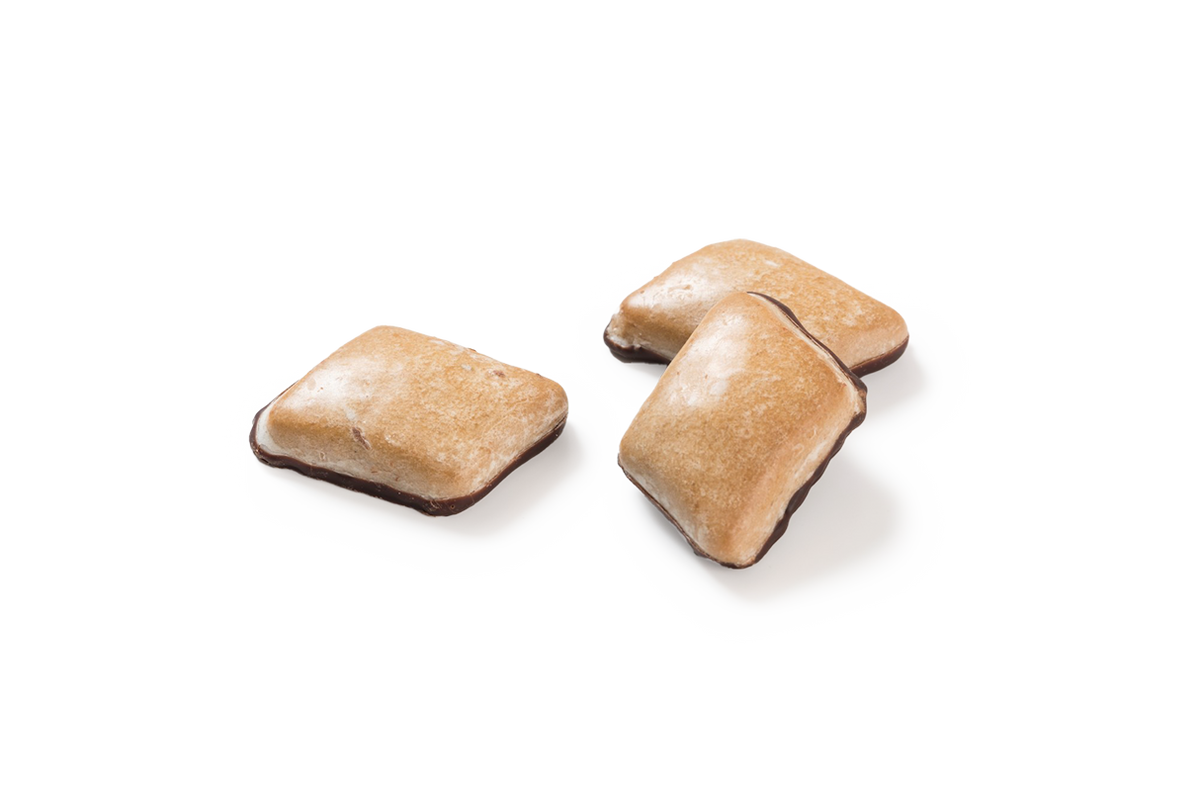 Produktaufnahme von drei Honig Leckerli. Die quadratischen, glasierten Lebkuchen zeichnen sich durch ihre helle Oberfläche aus und sind an der Unterseite mit einer Schicht Zartbitterschokoladenkuvertüre versehen. 