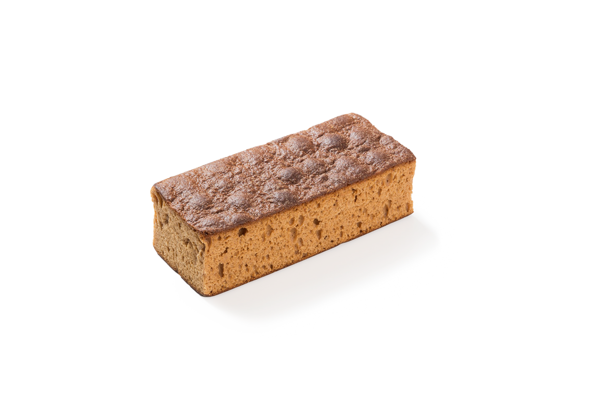 Produktaufnahme eines einzelnen, länglichen, rechteckigen Honigkuchens (auch als Frühstückskuchen bekannt). Das Gebäckstück zeigt eine charakteristische dunkelbraune, blasige Kruste auf der Oberseite sowie eine feinporige, hellbraune Teigstruktur an den Schnittflächen.