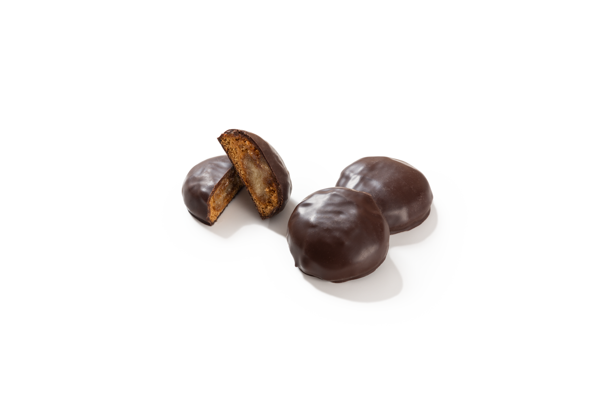 Produktaufnahme von drei runden Marzipantalern. Zwei Taler sind vollständig mit dunkler Schokolade überzogen. Ein dritter Taler ist halbiert und gibt den Blick auf den hellen Marzipankern und den Lebkuchenteig im Inneren frei.